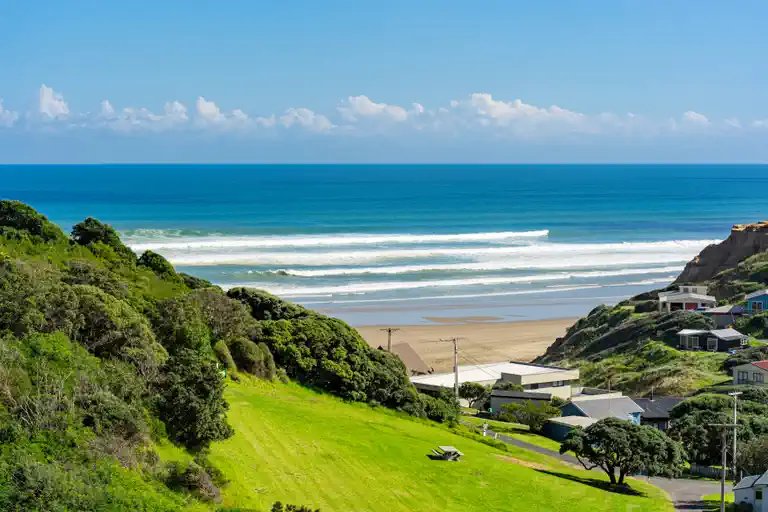 Bach community on the cliffs above the beach, Baylys Beach surf spot, Northland West, New Zealand.