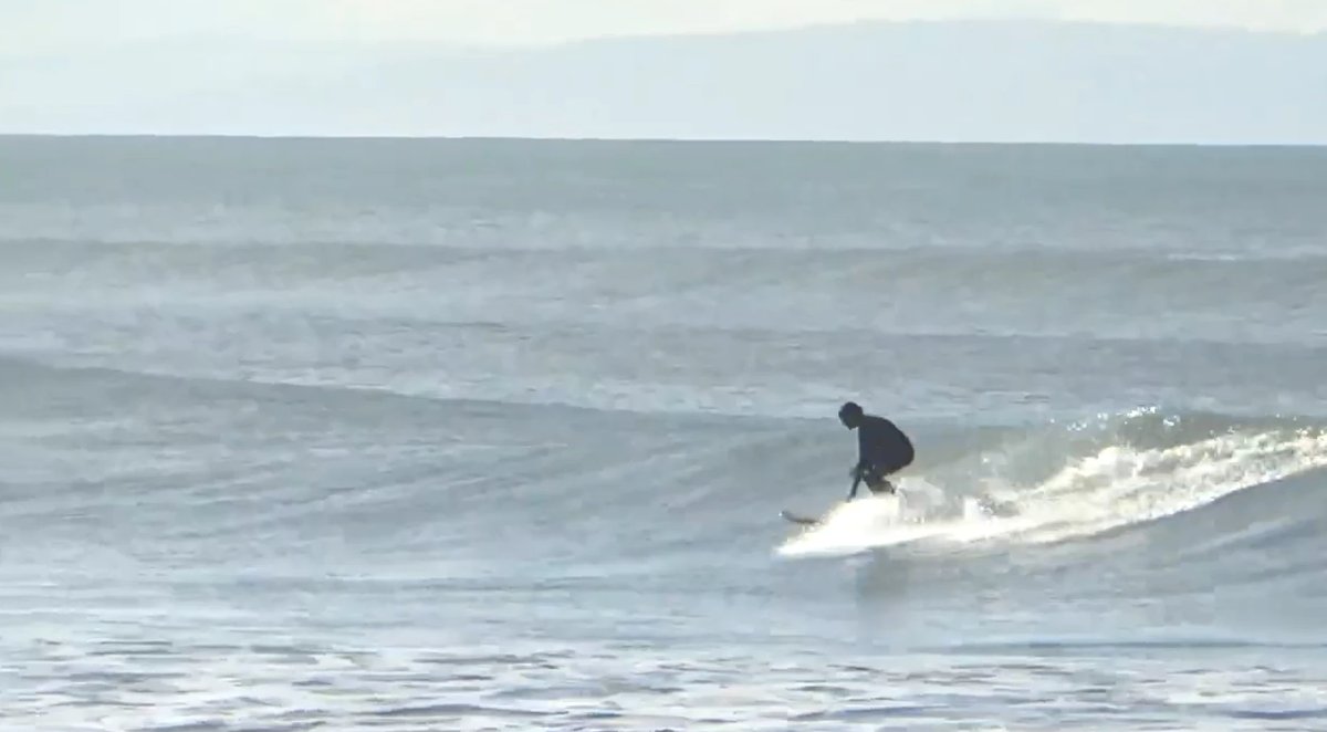 A longboarder trimming along a clean little wall on a soft grey morning, classic Sumner cruising, Sumner / Scarborough surf s